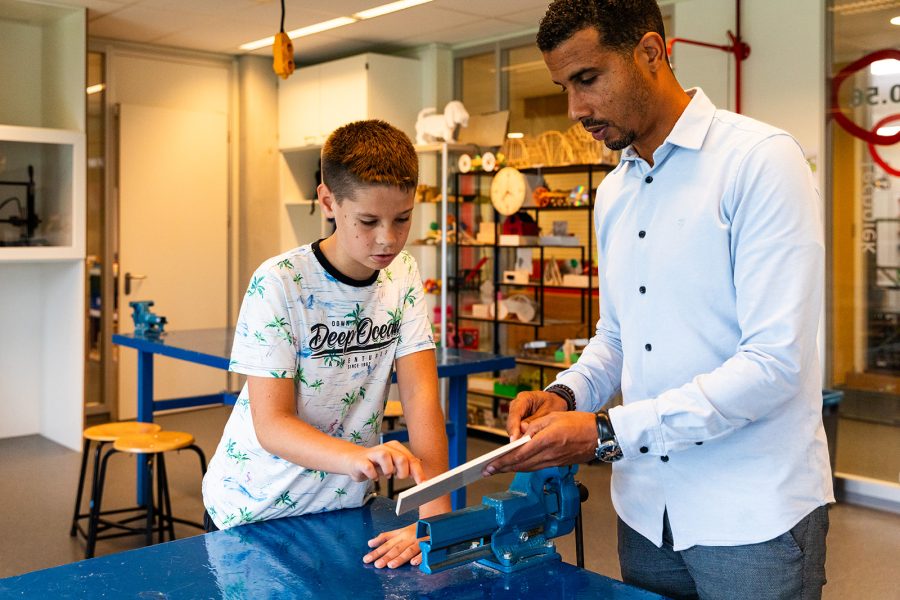 Docent helpt leerling in de techniekles bij Houtens ontwerpen en maken